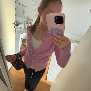 Rosa kofta med blommiga knappar - Säljer en super gullig stickad kofta med pärlknappar. Lite nopprig men inget man tänker på💞🫶🏻❣️Passar bra till både jeans och kjol.