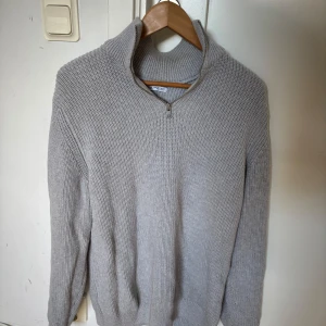 Grå stickad tröja från Zara - Säljer en stilren grå stickad tröja från Zara med zip vid halsen. Tröjan har en klassisk som passar till det mesta. Nästan aldrig använd.