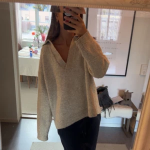 Beige stickad tröja med v-ringning - Säljer en mysig beige stickad tröja med v-ringning. Tröjan har långa ärmar och en avslappnad passform, perfekt för kyligare dagar. Passar bra till både jeans och kjol.