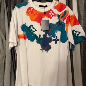 Vit t-shirt med färgstänk - Säljer en vit t shirt med färgstänk och en fin design storlek XL den passar även L