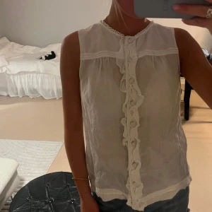 Vit blus med spets från Massimo Dutti - Supersöt vit blus från Massimo Dutti med ärmlös design och fina spetsdetaljer längs knäppningen framtill. 