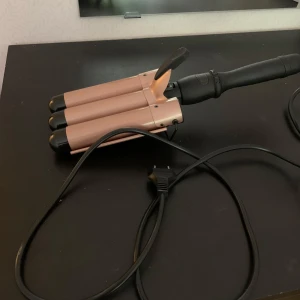 Trippelt vågtång för håret, roséguld - Säljer en elektrisk trippel vågtång i snygg roséguld med svarta detaljer. Perfekt för att skapa beach waves och volym. Har svart handtag och lång sladd för smidig styling 🫶💕