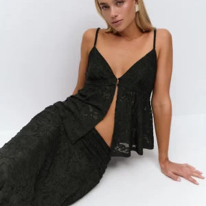 Svart spetsig linnetopp från Gina Tricot - Svart linnetopp med tunna axelband och v-ringning från Gina Tricot. Toppen har ett genombrutet spetsmönster, liten knapp framtill och lätt utsvängd passform. Perfekt för att skapa en chic och trendig look. Säljer eftersom jag inte hittar ett tillfälle att använda den.