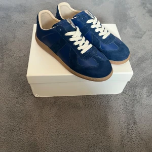 Maison Margiela Gats - Säljer ett par helt nya Maison Margiela Gats i blå mocka/läder. Aldrig använda! Originalkartong & kvitto finns. Anledningen till det låga priset är att jag råkade skada original lådan så den har bucklor, repor. Skorna är dock i toppskick och har bara provats på.   🟦 Storlek: 42-43 🛍️ Nypris: ca 8000 💸 Mitt pris: 3000 