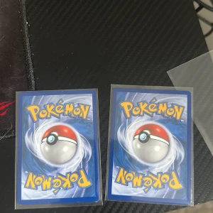 Pokémonkort - Två klassiska Pokémonkort med den ikoniska Pokébollen på baksidan. Perfekt för samlare eller dig som vill utöka din kortlek och spela med vänner. Korten är i bra skick och redo för nya äventyr!