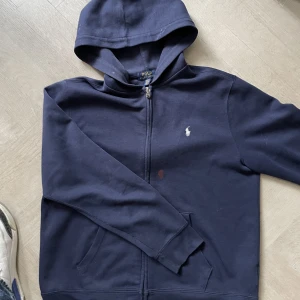 Ralph lauren polo mörkblå zip hoodie - En mörkblå polo zip hoodie i storlek M. Passar också S. Den är i bra skick men har en röd fläck vid bröstet. Priset kan justeras🙌