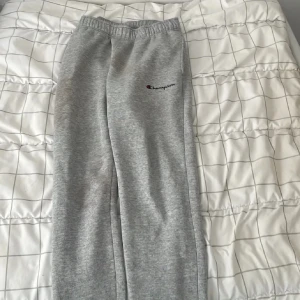 Grå mjukisbyxor från Champion XS - Grå mjukisbyxor från Champion i storlek XS. Byxorna har elastisk midja och broderad Champion-logga på ena benet. Tillverkade i mjukt material som är perfekt för chill eller träning. Klassisk rak passform och enkel stil.