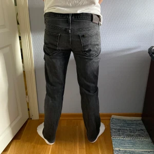 Svarta jeans från Lee, straight fit - Säljer ett par svarta jeans från Lee med klassisk femficksdesign och raka ben. Modellen är 179
