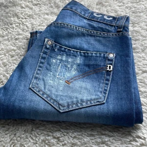 Dondup - Snygga blå jeans från Diesel med coola slitningar på bakfickan och klassiska kontrastsömmar. Jeansen har en klassisk femficksdesign och detaljer i silverfärg. Perfekta för en avslappnad och trendig look.