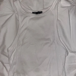 Vit ribbad linnetopp från Zara - Säljer en stilren vit ribbad linnetopp från Zara. Toppen har en tight passform och går att styla med mycket!😍