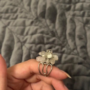 Statementring med stenar och pärlor - Unik statementring i silverfärgad metall med stora, klara stenar och pärlor i en blomliknande form. Ringen har en cool, handgjord känsla och är perfekt för dig som vill sticka ut. Justerbar storlek och riktigt snygg detalj till din outfit.