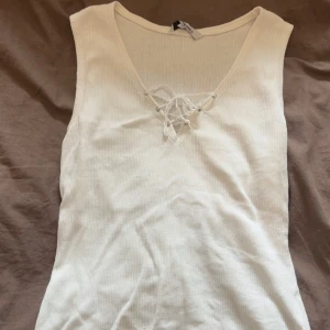 ‼️RESERVERAD‼️Vit ribbad linnetopp med snörning - Säljer en vit ribbad linnetopp med snygg snörning framtill vid v-ringningen. Toppen är ärmlös och har en mjuk, stretchig känsla som passar perfekt till jeans eller kjol. Enkel men ändå med en cool detalj framtill. Storlek M men skulle säga att den passar s-m❤️