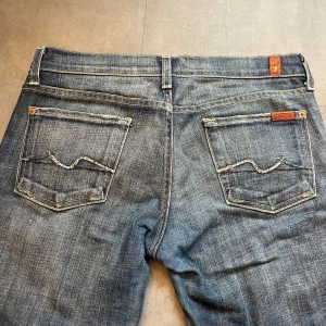 Lågmidjade jeans - Fina lågmidjade utsvängda jeans från 7 for all mankind, lite små på mig, broderade fickor, lite slitna längst ner men annars bra skick