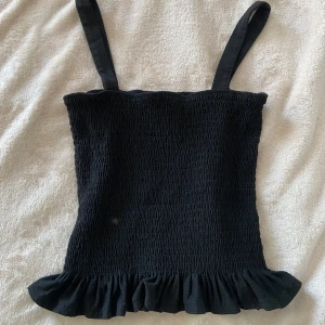 Svart smockad linnetopp från H&M - Supersöt svart linnetopp från H&M med smockad struktur, volang och breda axelband💕