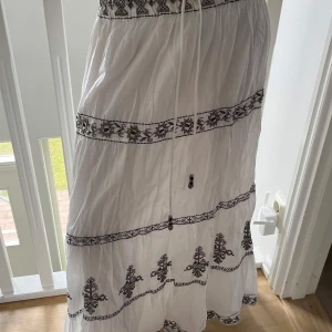 Vit maxikjol med broderade detaljer - Superfin vit maxikjol med broderade blommor och mönsterband. 