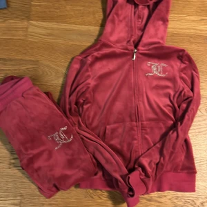 Röd velour set från juicy catutre i storlek 156 - Säljer en snygg röd velour set från Juicy Couture i storlek 156 med glittrande stenar som bildar loggan på bröstet och ryggen. Perfekt för en avslappnad och stilren look. Hoodien har dragkedja och en mysig huva.  KAN FÖRHANLDA PRISET!