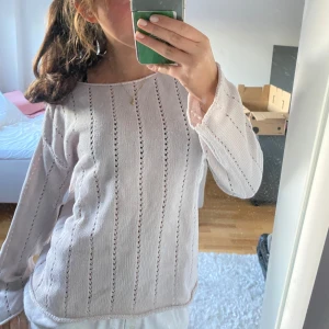 Vit stickad tröja - Säljer en vit stickad tröja med ett diskret hålmönster. Tröjan har långa ärmar och en bekväm passform, perfekt för kyligare dagar. En stilren och enkel design som passar till det mesta.