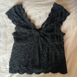 Trendig spets topp - Säljer denna trendiga spetstoppen från Stradivarius. Toppen har en djup v-ringning och korta ärmar och är helt i spets. Perfekt för vardag och fest!💕 Skriv vid frågor!