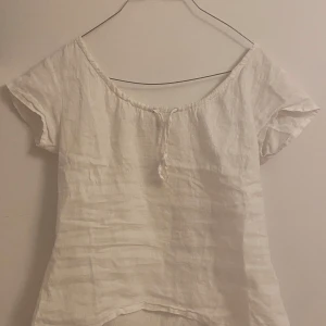 Vit blus från InWear - Säljer en luftig vit blus från InWear i linne. Blusen har korta ärmar och en knytning framtill vid halsen. Perfekt för varma dagar! Lite större i storlek men går att justera. 💞💞