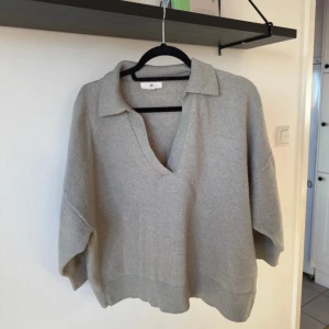 Grå/mintgrön tröja från H&M - Säljer en stilren grå tröja från H&M med v-ringning och krage. Tröjan har en avslappnad passform och är tillverkad i ett mjukt material som passar perfekt för kyligare dagar. Lite nopprig vilket kan ses på bilderna, ingenting man tänker på. Den är grå/mintgrön