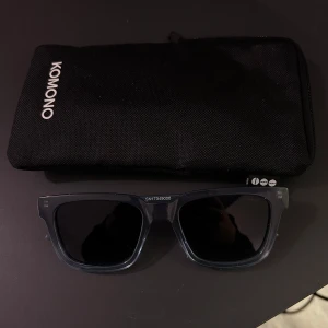 Grå/blåa solglasögon från Komono - Snygga svarta solglasögon från Komono med en klassisk fyrkantig form. Fodralet följer med, skick 10/10 använda 2ggr nypris 699kr. Priset är diskuterbart 