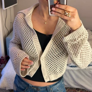 Beige stickad kofta från H&M Divided - Säljer en  beige stickad kofta från H&M Divided. Koftan har ett öppet stickat mönster och knappar framtill. 