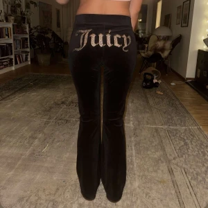 Svarta Juicy Couture byxor - Säljer ett par svarta juicy byxor med ett litet skärp framtill med en silverdetalj och rhinestones på rumpan. Byxorna är i storlek M men passar även S. Super bra skick💗