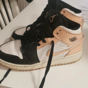 Nike Air Jordans i svart, vitt och beige - Snygga Nike Air Jordans i en cool färgkombination av svart, vitt och beige. Skorna har klassisk snörning och den ikoniska Air Jordan-loggan på sidan. Perfekta för dig som vill ha en stilren och sportig look.