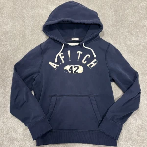 Abercrombie & Fitch Hoodie - Tja! Säljer denna feta mörkblå A&Fitch hoodie med riktigt snygga slitningar! Hoodien är i fint skick, inga defekter. Size L passar M, modellen på bilden är 182cm lång ish. Skriv vid funderingar!