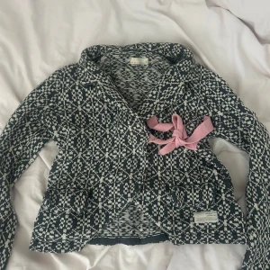 Mönstrad kofta från Odd Molly - Säljer en snygg mönstrad kofta från Odd Molly i svart och vit. Koftan har långa ärmar och en fin broderad detalj med en fågel på armen. Den har också en rosa rosett framtill. Jätte fin och använd få gånger. Står ingen storlek men den passar mug bra och tajt som brukar ha stolar xs eller s💕🌸