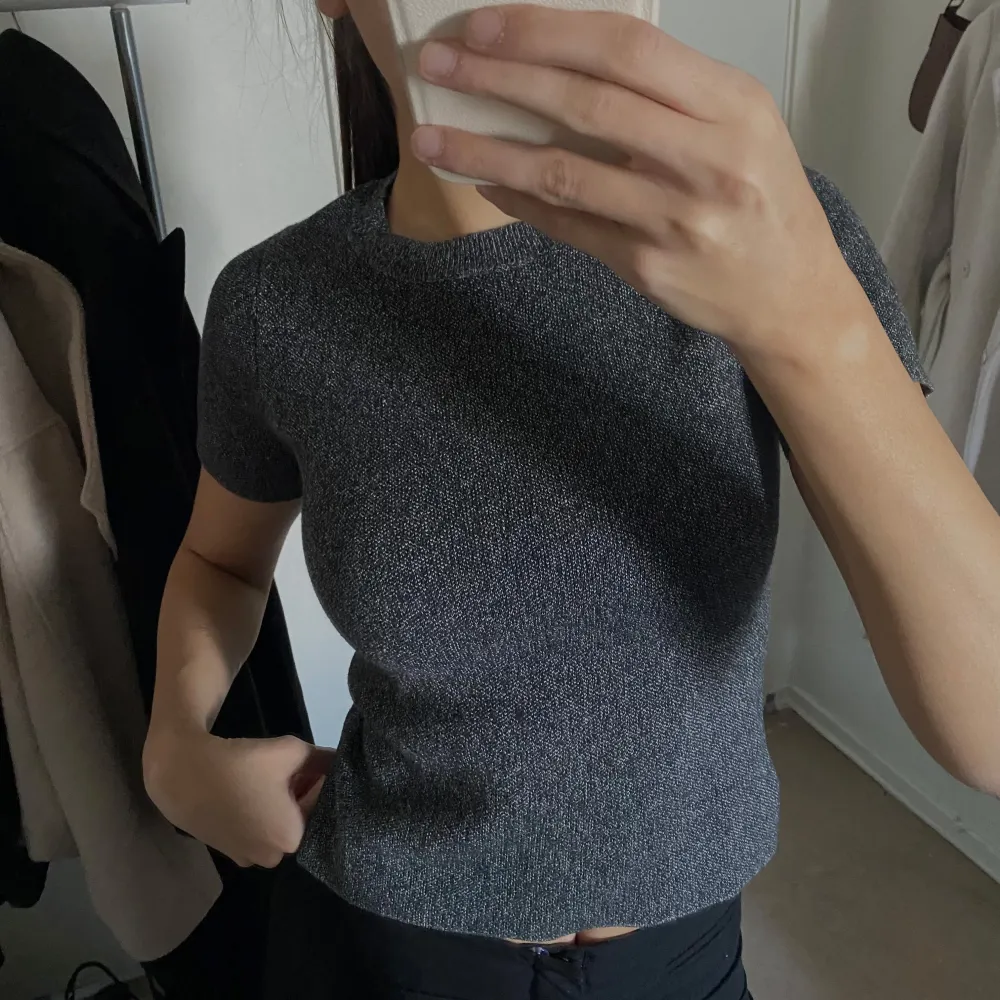 Säljer en stilren grå ribbad topp med korta ärmar. Perfekt för en enkel och snygg look. . Neuletakit & Villapaidat.