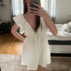 Vit klänning med volangdetaljer - Säljer en söt vit klänning med volangdetaljer och v-ringning. Klänningen har en kort längd och är perfekt för varma dagar eller bla studenten.🤍Ej använd, endast provad. Nypris 650kr.