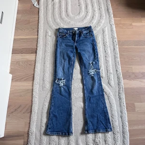Blå bootcut jeans med slitningar - Snygga blå bootcut jeans med slitningar på knäna. Köpt på Vinted, men säljer tyvärr vidare pågrund av att de var för små.💗 