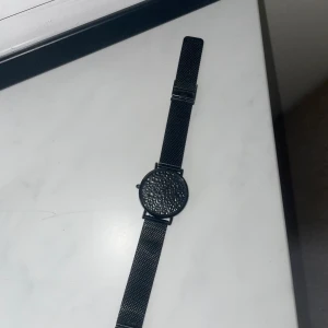 Svart klocka från black oak - Stilren svart klocka från Black Oak med ett unikt mönstrad urtavla och matchande svart mesharmband. Perfekt för en minimalistisk look.