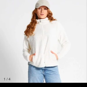 Fleece  - Mysig vit fleece med dragkedja och hög krage. Perfekt för kyliga dagar. Tröjan har en avslappnad passform och är långärmad, vilket gör den idealisk för lager-på-lager-stil.