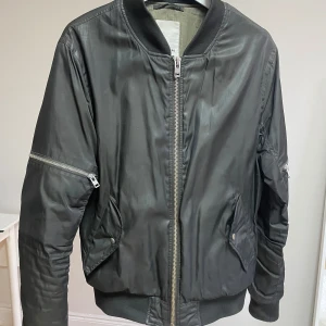 Mörkgrön bomberjacka från J.Lindeberg - Säljer en stilren mörkgrön/olivfärgad bomberjacka från J.Lindeberg. Jackan har lite vaddering så den passar perfekt för våren eller höst.