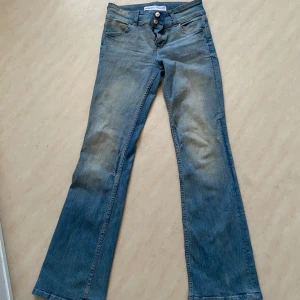 Blå bootcut jeans från Bershka - Snygga blå bootcut jeans från Bershka med låg midja och klassisk femficksdesign. Jeansen stängs med dragkedja och knapp. Perfekta för en avslappnad stil.