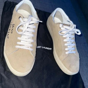 Beige Saint Laurent sneakers mocka - Snygga beige sneakers från Saint Laurent. Har haft de i ungefär 5 månader pga att de blev för små. skorna har bra skick och det medföljer en dustbag. Hör gärna av dig vid minsta lilla fundering😊