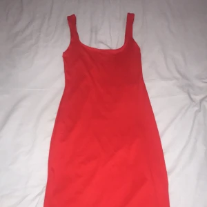 Röd Van Der Rock klänning med slits - Snygg röd klänning från Missäy med smala axelband och en enkel, figurnära passform. Klänningen har en slits på sidan som ger en extra touch. Perfekt för dig som vill sticka ut med en färgstark look.