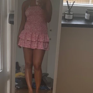 Rosa smockad kortklänning med volang - Supersöt rosa  tubklänning från GinaTricot med  en volang nertill. Ny med prislapp. Stl L men passar allt från S-L då den är  töjbar