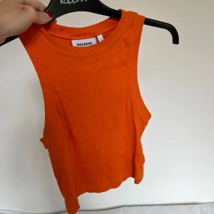 Orange ribbad linnetopp från Weekday - Snygg orange ribbad linnetopp från Weekday. Passar perfekt till solbrännan. Modellen är ärmlös med rund halsringning och croppad passform. Perfekt för varma dagar eller att styla lager på lager. Sparsamt använd, som ny💕💕