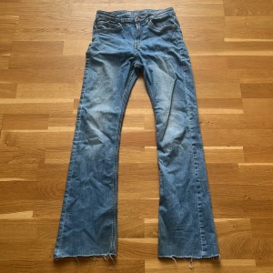 Blå bootcut jeans från LAB Industries - Snygga blå jeans från LAB Industries i klassisk bootcut-modell. Jeansen har råa, fransiga benslut som jag klippt själv och en ljus tvätt med slitningar. Tillverkade i bomull och har fem fickor samt dragkedja och knapp framtill. Perfekta för en avslappnad och trendig look.