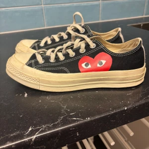 Svarta Converse x CDG Play sneakers - Svarta låga Converse sneakers från Comme des Garçons Play. Vita snören och sula, klassisk rund tå och platt sula. Använda max 10 gånger pga de är för små för mig. 