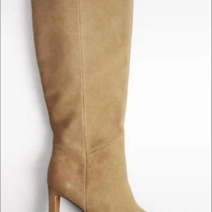 Beiga mockastövlar med klack, slutsålda på NAKDs hemsida. Köpte mina för 1300 och knappt använda🌸 förutom en lite skada se bild 2☺️ - Stilrena beiga stövlar i mocka med hög klack och rund tå. Snyggt minimalistisk design som går upp till knäet och passar perfekt till jeans eller klänning. Ger en chic och trendig look till din outfit.