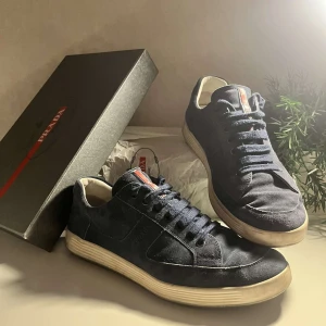 Mörkblå sneakers från Prada mocka - Ett par Prada skor i väldigt bra skick. Nypris - ca 6000kr, box ingår! Skorna är storlek 42 men passar även 43. KOM GÄRNA MED BUD!
