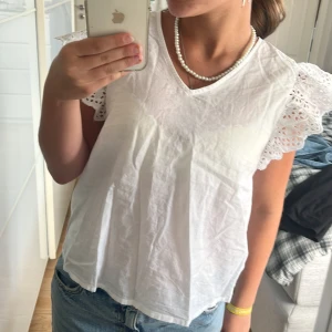 Vit blus med spetsärmar från ONLY - Superfin vit blus från ONLY i bomull med v-ringning och korta ärmar i broderad spets. Luftig och lätt modell med romantiska detaljer på ärmarna som ger en söt och somrig vibe. Perfekt att matcha med jeans eller kjol för en fräsch look.  Storlek xs. Använd få gånger💗