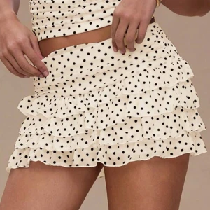 Prickig volangkjol från H&M - Supersöt kort volangkjol från H&M i beige med svarta prickar. Kjolen har flera lager volanger och resår i midjan. Den är i storlek S/XS. 💗💗