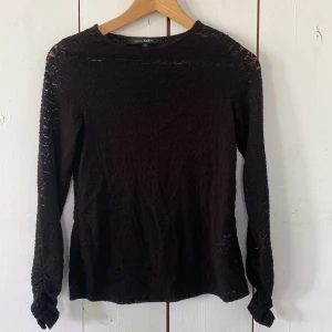 Svart spetsblus från KappAhl XS - Supersnygg svart blus från KappAhl i spets med lång ärm och rund hals. Blusen har ett transparent blommigt mönster som ger en cool och elegant vibe. Perfekt att styla med jeans eller kjol för en trendig look. Den är även scrunchad längst ner på ärmen (bild 5)