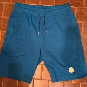 Moncler Mjukis Shorts - Tjena! Säljer dessa feta Moncler mjukis shorts med hel vitt emblem. Endast legat i garderoben så dem är helt oanvända. Köpta för ett par månader sedan för 2,500kr!😁👏 Väljer du att betala direkt via Swish kan jag gå ner lite i pris eftersom vi då slipper all väntetid som tillkommer via betalning genom Plick!🏆 Skicka ett PM vid frågor eller funderingar.