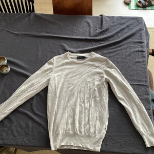 Ljus grå långärmad tröja  - Klassisk ljus grå långärmad tröja. i tunn och mjuk bomull. Enkel design med rund halsringning och ribbade muddar vid ärmslut och nederkant. Perfekt för lager-på-lager och stilrena outfits.